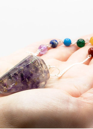 Péndulo de orgonita de amatista con 7 chakras sostenido en mano para mostrar tamaño real y detalle