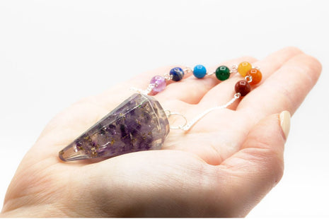 Péndulo de orgonita de amatista con 7 chakras sostenido en mano para mostrar tamaño real y detalle